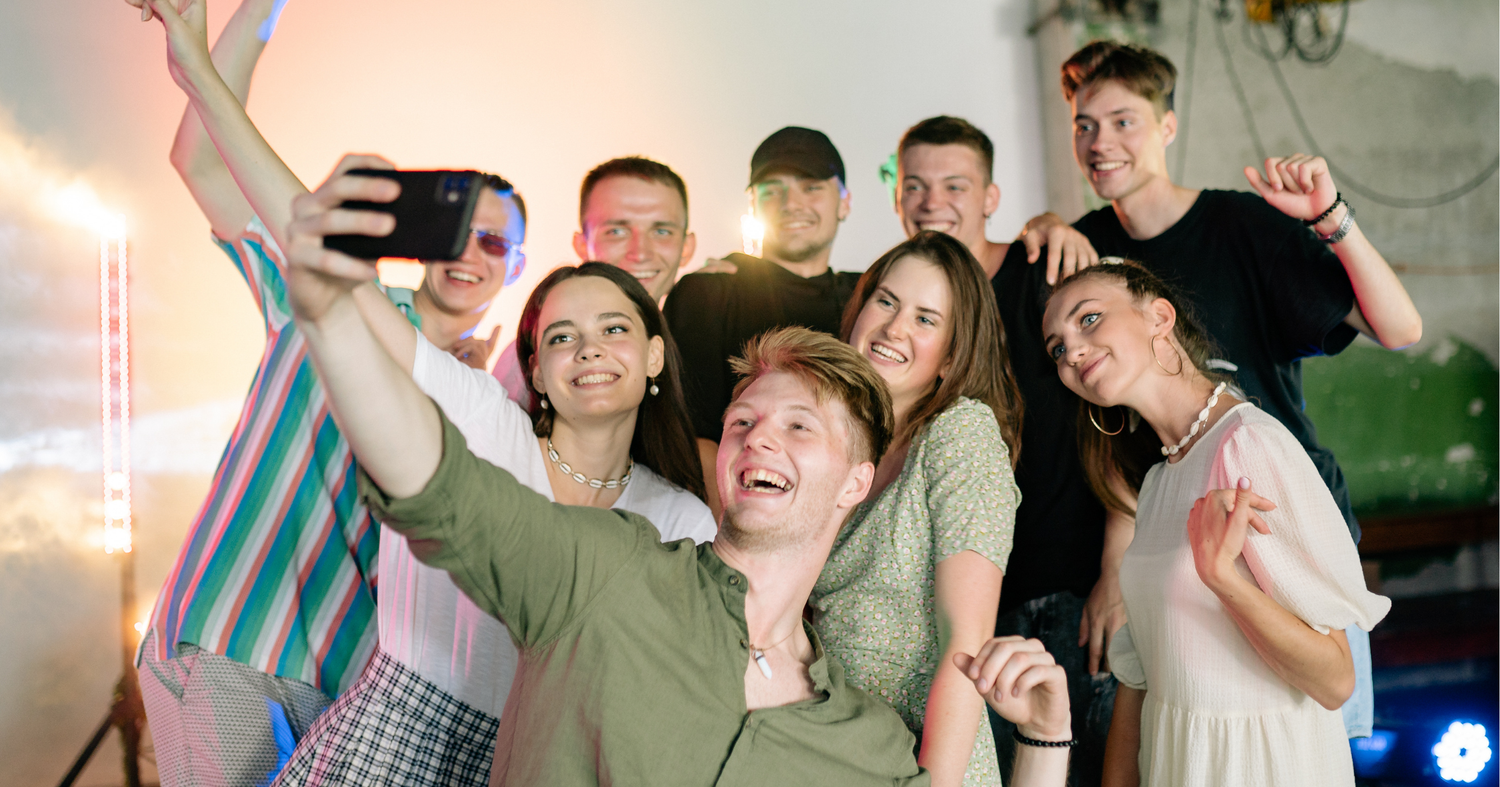 A joyful group of young adults, representing the next generation of church leaders, smiling and taking a selfie together at a ministry event.